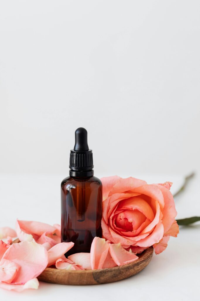 pexels-photo-4041391-4041391 Elegant dropper bottle with pink rose petals on a wooden plate, perfect for aromatherapy or skincare.